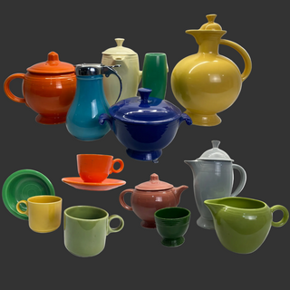 Collection of colorful ceramic tea pots and mugs on a dark background